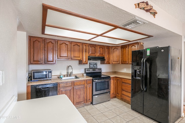 kitchen featuring light tile patterned flooring, black appliances, sink, and a textured ceiling