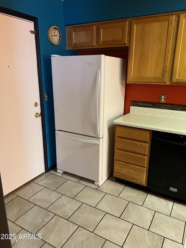 kitchen with white fridge, light tile patterned floors, and black dishwasher