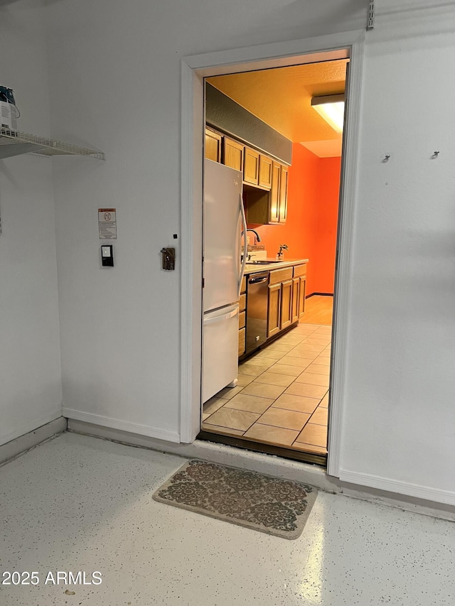 kitchen featuring dishwashing machine, white refrigerator, and sink