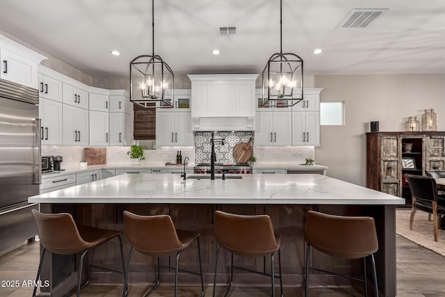 kitchen featuring hanging light fixtures, a kitchen island with sink, dark hardwood / wood-style floors, and high quality fridge