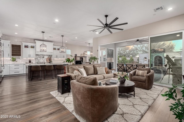 living room featuring ceiling fan with notable chandelier and dark hardwood / wood-style flooring