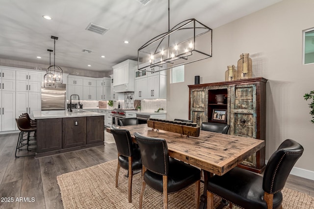 dining room with sink, dark hardwood / wood-style flooring, and a notable chandelier