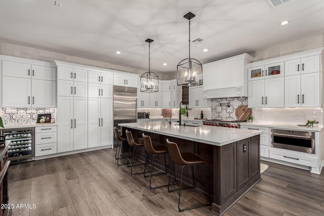 kitchen with pendant lighting, white cabinetry, an island with sink, dark hardwood / wood-style floors, and a breakfast bar