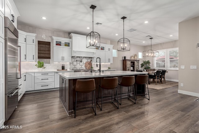 kitchen with white cabinets, a center island with sink, and hanging light fixtures