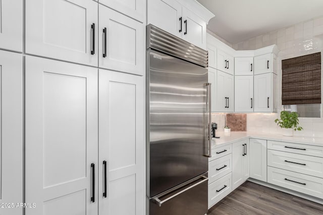 kitchen with tasteful backsplash, white cabinets, dark hardwood / wood-style floors, and stainless steel built in refrigerator