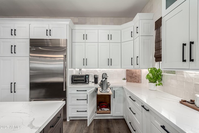 kitchen featuring decorative backsplash, light stone countertops, white cabinetry, and stainless steel built in refrigerator