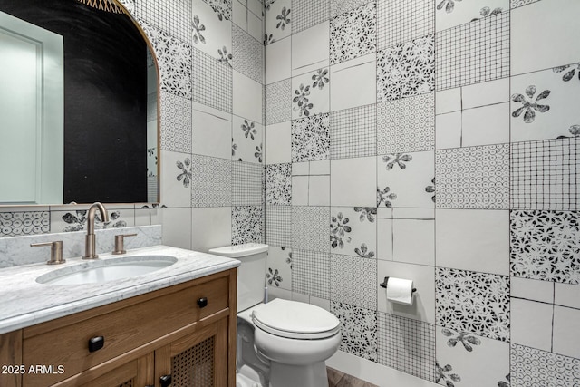 bathroom featuring toilet, tile walls, and vanity