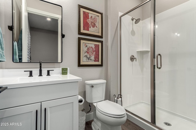 bathroom with toilet, vanity, and a shower with door