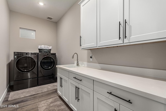 laundry room featuring cabinets, sink, wood-type flooring, and washing machine and dryer