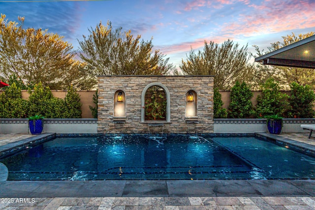 pool at dusk featuring a patio area