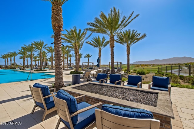 view of patio with a community pool, a mountain view, and a fire pit