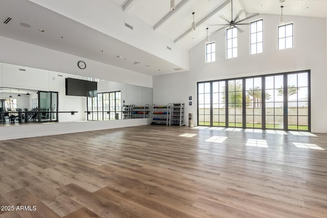 workout area with ceiling fan, hardwood / wood-style flooring, and high vaulted ceiling