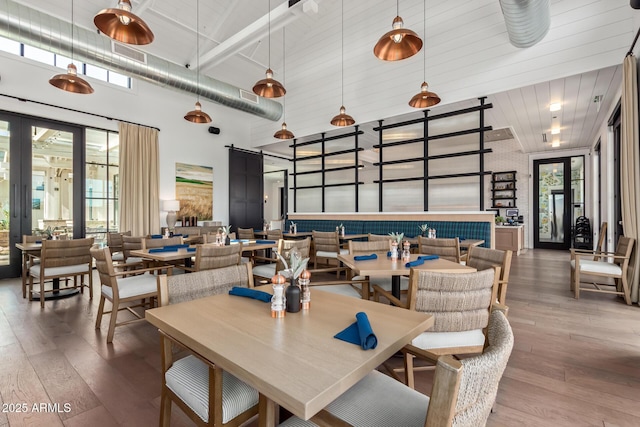 dining room with a barn door, french doors, a towering ceiling, and hardwood / wood-style flooring