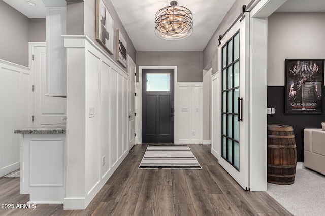 interior space with a barn door, dark hardwood / wood-style flooring, and an inviting chandelier