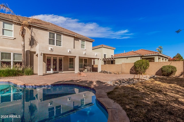 rear view of house featuring french doors, a patio area, and a fenced in pool