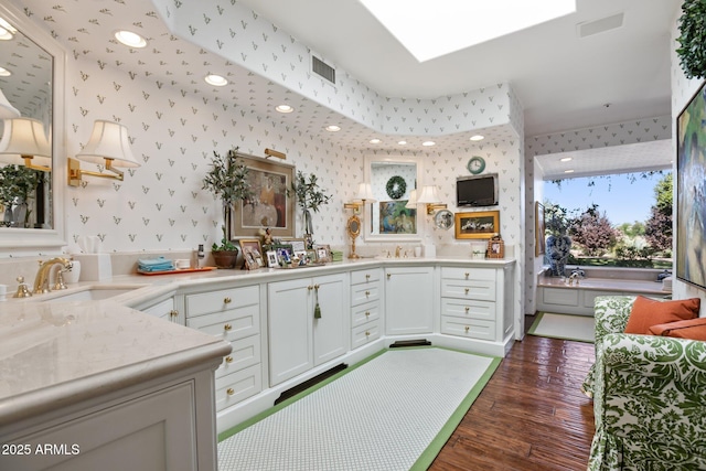 full bathroom featuring wallpapered walls, a skylight, visible vents, wood finished floors, and a sink