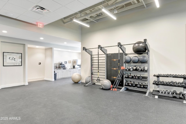 workout area featuring a paneled ceiling, recessed lighting, a high ceiling, visible vents, and baseboards