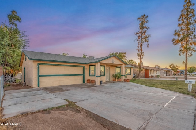 6415 W Roosevelt St, Phoenix, AZ 85043 - ranch-style home with driveway, an attached garage, stucco siding, and a front lawn