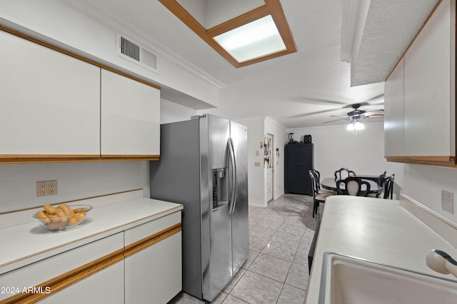 6415 W Roosevelt St, Phoenix, AZ 85043 - kitchen with stainless steel fridge with ice dispenser, light countertops, white cabinetry, ceiling fan, and light tile patterned floors