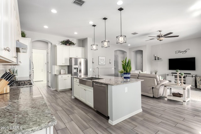 kitchen featuring ceiling fan, arched walkways, appliances with stainless steel finishes, and a sink