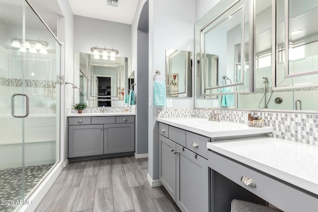 bathroom with vanity, visible vents, wood finish floors, a stall shower, and tasteful backsplash