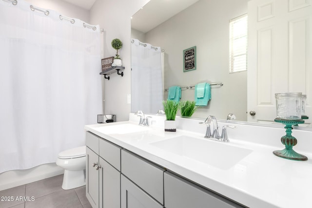 bathroom featuring tile patterned floors, double vanity, toilet, and a sink