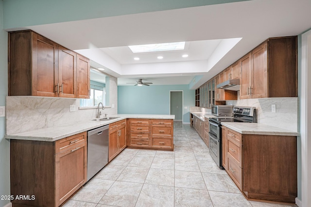 kitchen featuring decorative backsplash, sink, stainless steel appliances, and a skylight