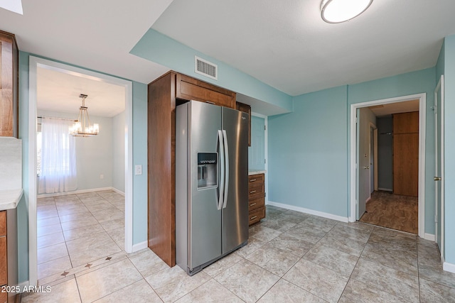 kitchen with a notable chandelier, stainless steel fridge, and decorative light fixtures