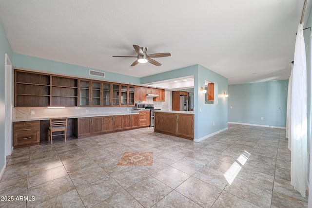 kitchen featuring decorative backsplash, kitchen peninsula, stainless steel appliances, ceiling fan, and built in desk