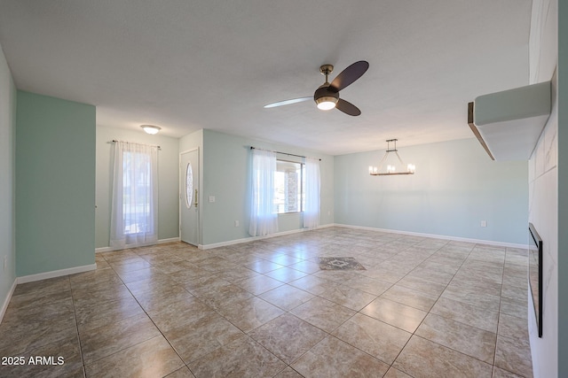 tiled spare room with ceiling fan with notable chandelier