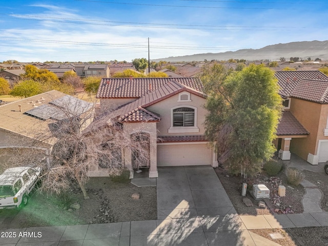 mediterranean / spanish house with a tiled roof, an attached garage, driveway, and stucco siding