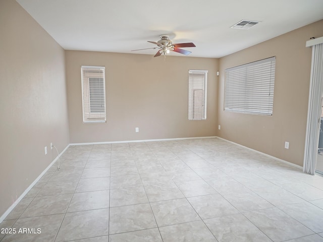 empty room with light tile patterned floors, baseboards, visible vents, and ceiling fan