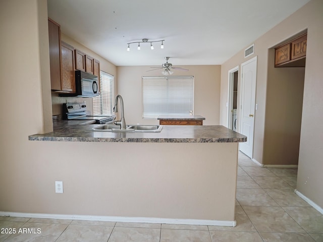 kitchen featuring visible vents, black microwave, a peninsula, electric range, and a sink