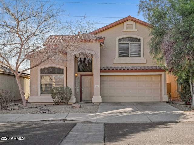 mediterranean / spanish home featuring concrete driveway, a tiled roof, an attached garage, and stucco siding