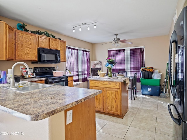 kitchen with black appliances, a sink, a kitchen island, light countertops, and light tile patterned floors