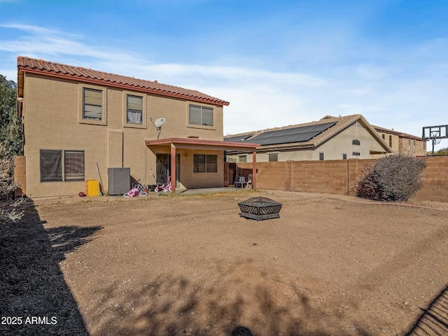 back of property with a patio, cooling unit, a fenced backyard, stucco siding, and a fire pit