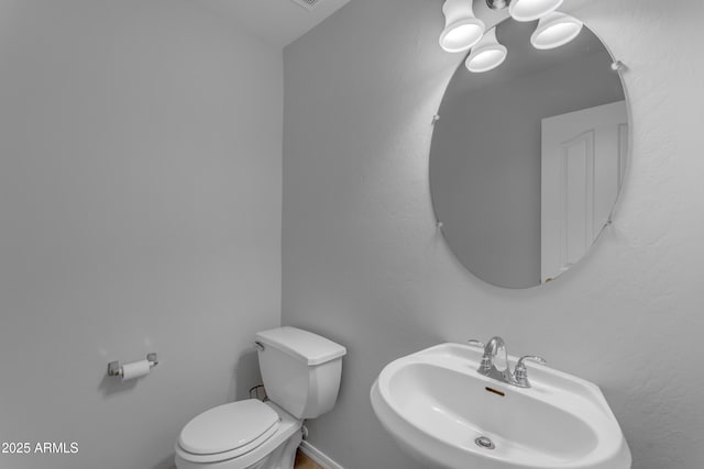 bathroom with baseboards, a sink, and toilet