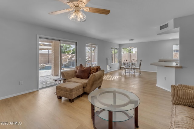 living room featuring light wood finished floors, baseboards, visible vents, and ceiling fan