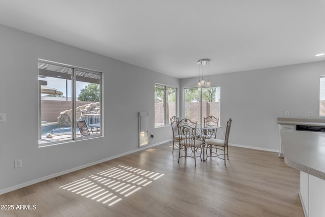 dining area featuring a chandelier, baseboards, and light wood finished floors