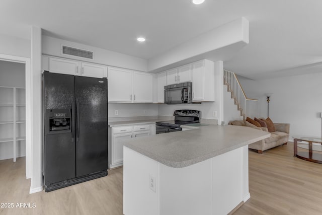 kitchen featuring visible vents, light countertops, light wood-type flooring, black appliances, and white cabinetry