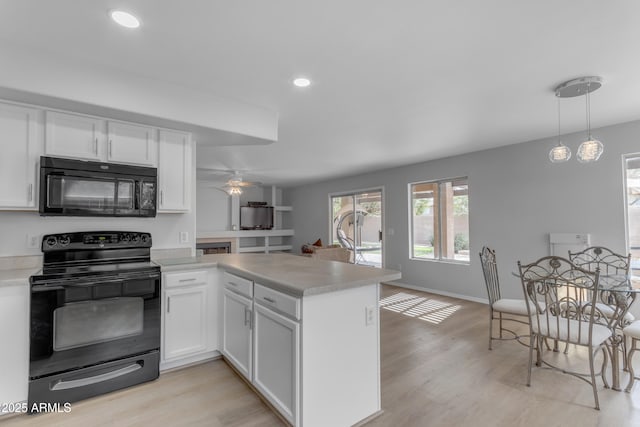 kitchen with white cabinets, light countertops, a peninsula, and black appliances