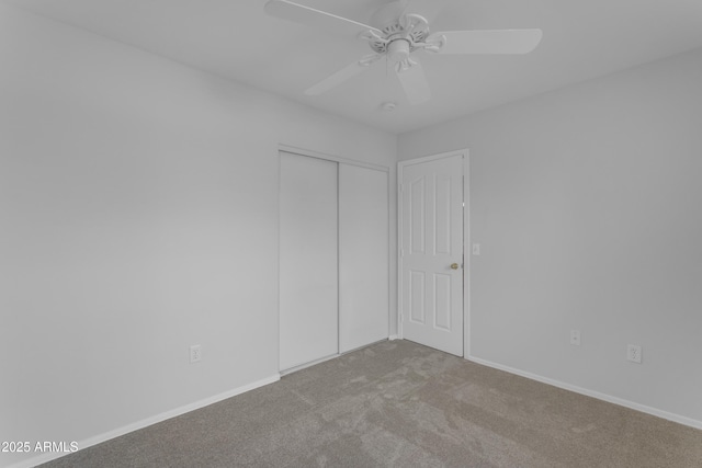 unfurnished bedroom featuring carpet, baseboards, ceiling fan, and a closet