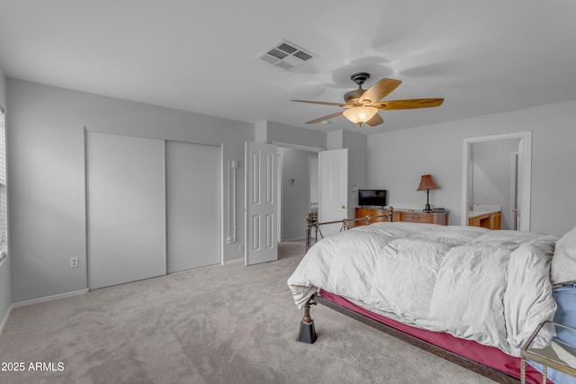 carpeted bedroom featuring a closet, visible vents, ceiling fan, and ensuite bath