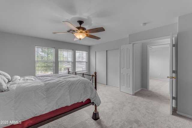 bedroom with ceiling fan, a closet, baseboards, and light colored carpet