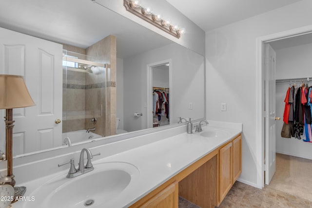 bathroom with double vanity, a sink, toilet, and baseboards