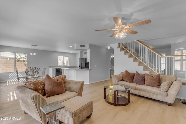 living area featuring a healthy amount of sunlight, light wood-style floors, stairs, and baseboards