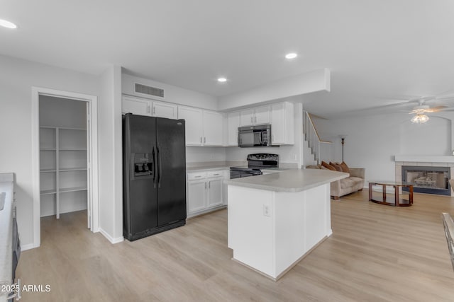 kitchen with visible vents, open floor plan, light countertops, black appliances, and a fireplace