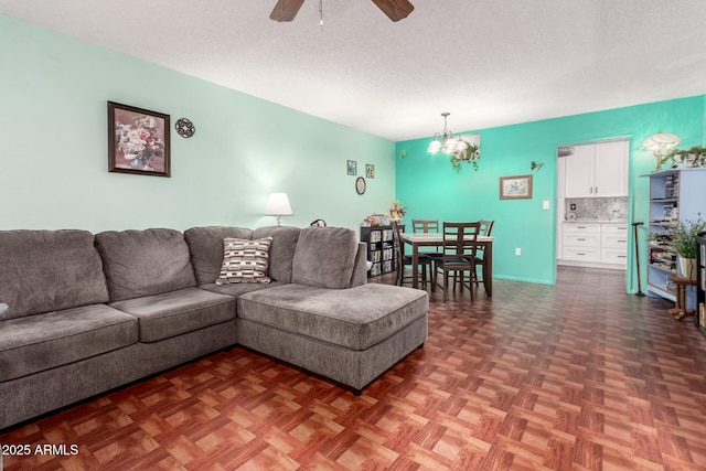 living room featuring ceiling fan with notable chandelier, dark parquet floors, and a textured ceiling