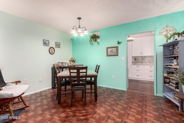 dining area with dark parquet flooring, a textured ceiling, and a notable chandelier