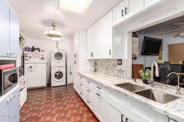 kitchen featuring stacked washer and clothes dryer, dark parquet flooring, sink, white cabinetry, and white refrigerator